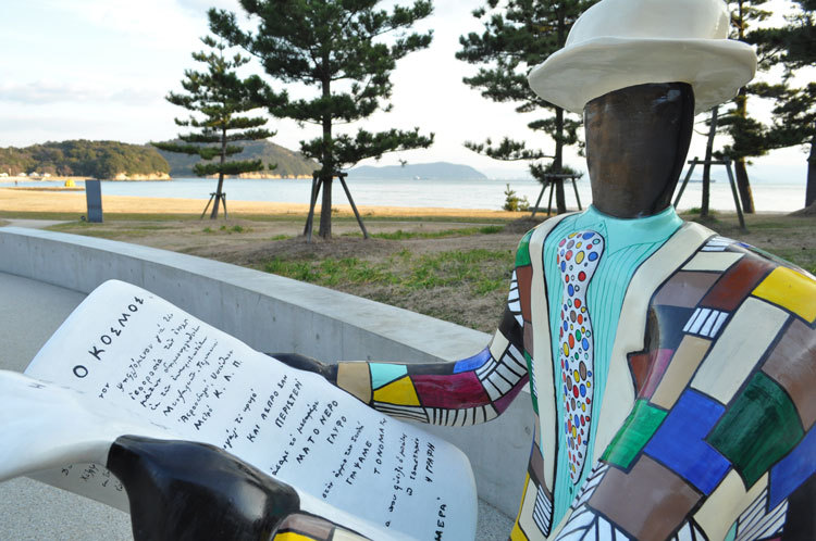 Colourful sculpture of a man reading a newspaper.