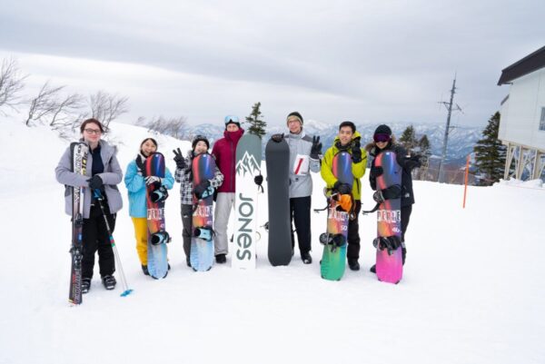 Akita Inaka School students holding skis and snowboards on a snowy slope