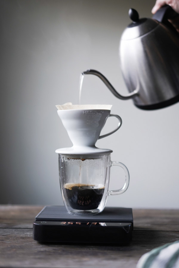 Hario V60 brewing over coffee with kettle and scale Hario V60 brewing over coffee with kettle and scale