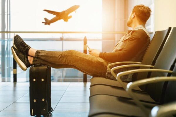 Traveller resting their feet on a suitcase in an airport departure lounge as a plane takes off