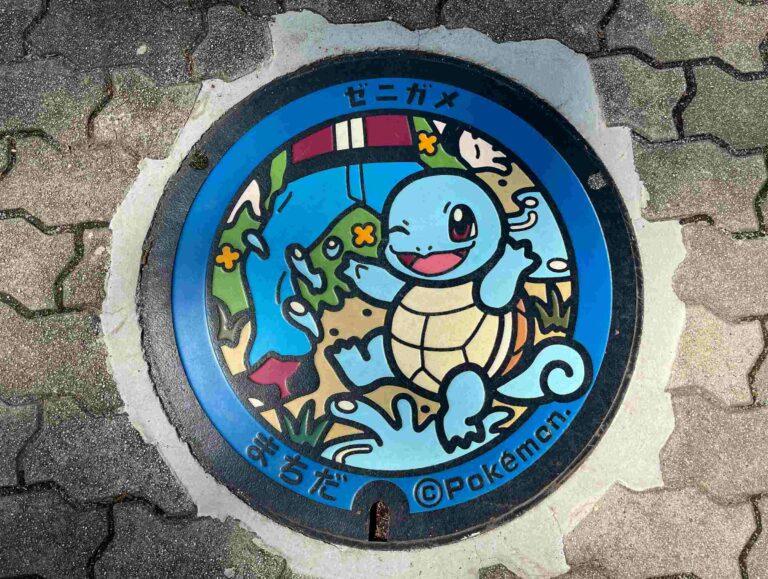Squirtle Poké Lid in Machida, Tokyo, painted in blue with the town name in Japanese, set into a brick pavement