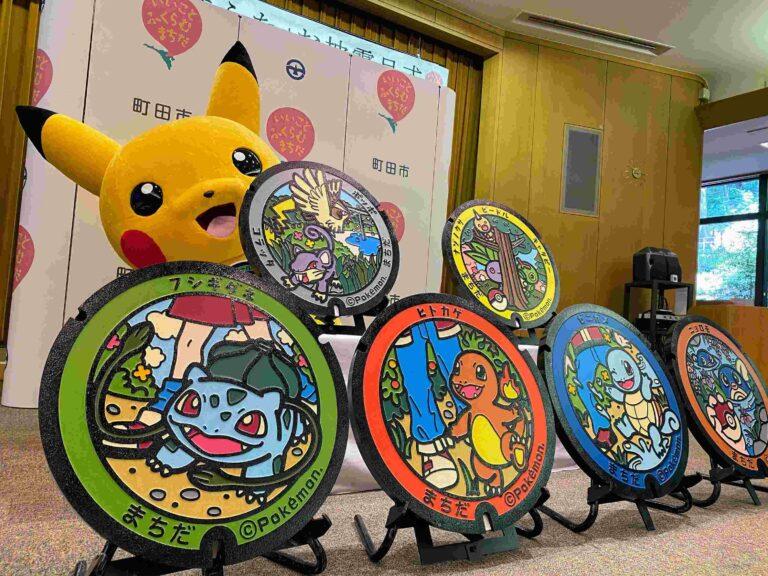 Pikachu mascot beside a display of Machida Poké Lids, including Bulbasaur, Charmander and Squirtle designs