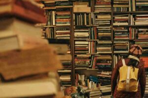 Reader browsing shelves filled with books in a Japanese bookstore or library, symbolising Tokyo literature culture and storytelling inspired by urban life across the city’s special wards.