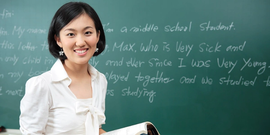 A teacher smiling while holding a book