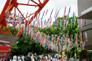 Colorful carp shaped koinobori streamers hanging in front of the red Tokyo Tower during a vibrant japanese summer festival in july.