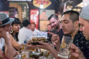 travelers enjoying yakitori and drinks inside a traditional japanese izakaya during a tokyo nightlife tour and bar crawl experience with okawari travels discovering local bars and street food culture in tokyo.