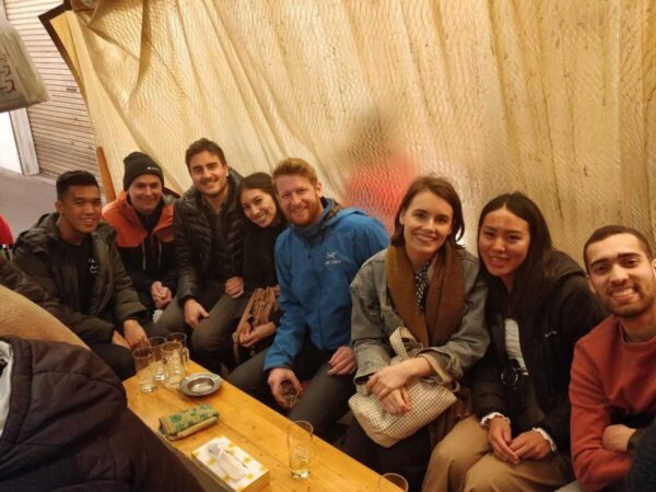 Okawari Travels guests posing together at a low izakaya table in Tokyo