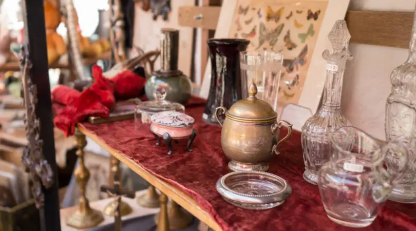 A table filled with antique items like teapots, plates, and vases