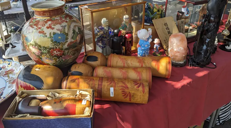 A table filled with antiques such as traditional Japanese wooden dolls and ceramics