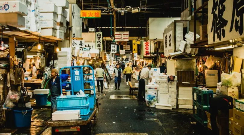 A busy alley of Toyosu market with various stalls selling fresh seafood