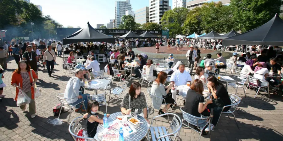 locals sit by a table in an open square during the Sapporo Autumn Fest