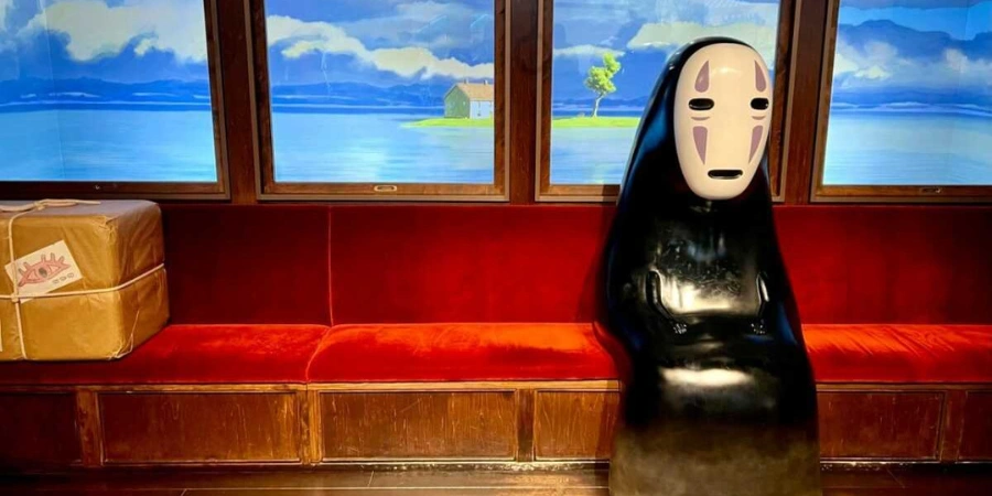No Face (the character) sitting on the red couch of the train