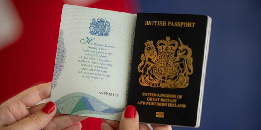 A person with red nail polish holding a British passport