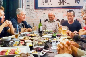 Bourdain in a dining table with locals