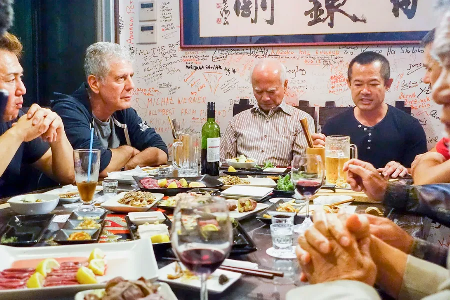 Bourdain in a dining table with locals