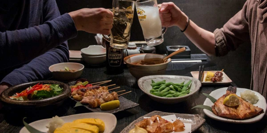 Two people toasting their drinks with their meals on the table