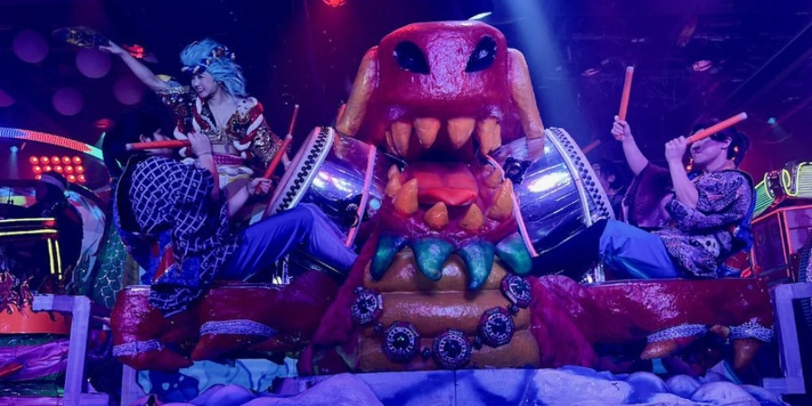 A dragon in a Samurai Restaurant with three people playing the Taiko Drums