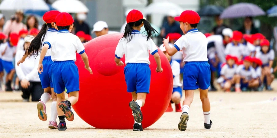 Elementary students playing with a big red ball in the playground