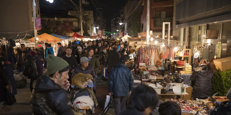 A bustling crowd stopping by different stalls, illuminated by lights