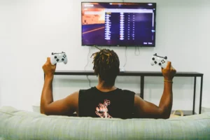 A guy sitting on a couch holding gaming consoles
