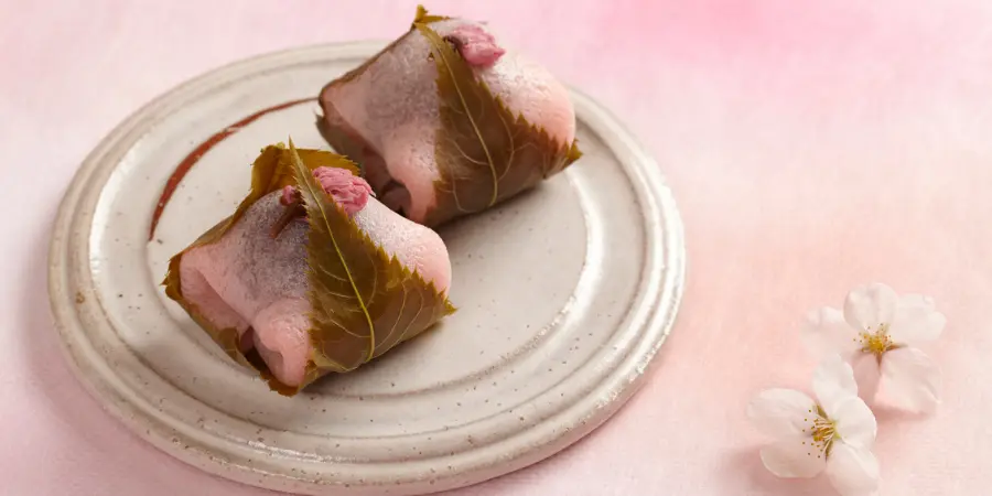 Sakura Mochi is a chewy, light pink glutinous rice ball filled with sweet red bean paste and wrapped in an edible pickled cherry blossom leaf.