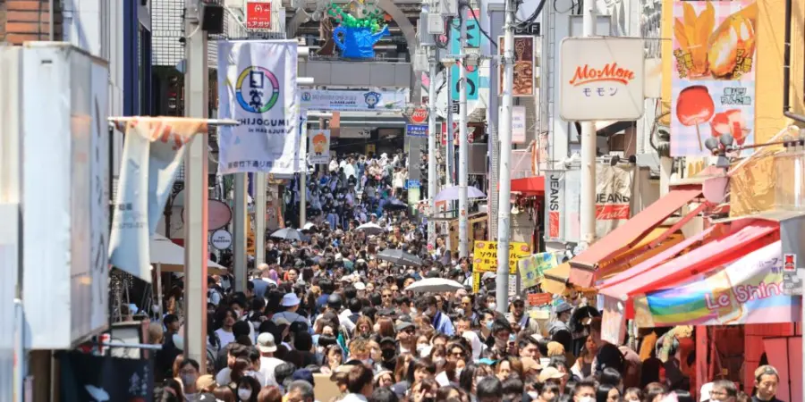 Busy shopping street packed with crowds during a holiday period, lined with colourful shop signs and storefronts.