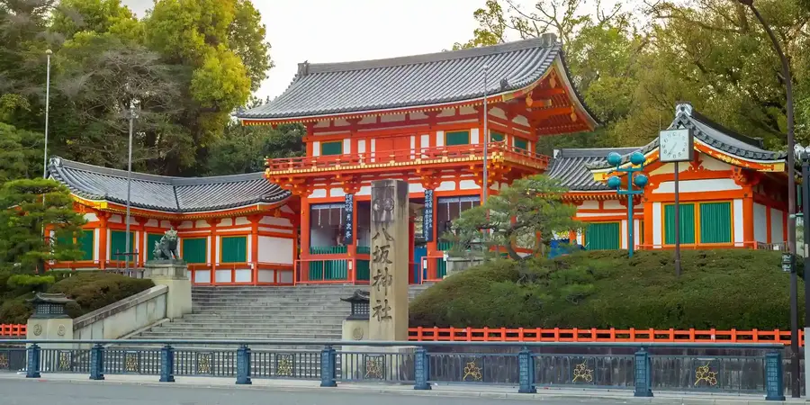 The Yasaka Shrine that showcases traditional Shinto architecture, featuring vibrant vermillion and white colors, intricate wooden carvings, and a sweeping roof with elegant eaves.