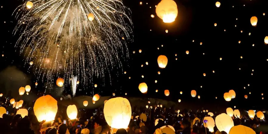Lanterns and fireworks illuminate the night sky