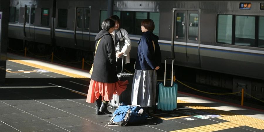 Three women standing at the platform with a lot of baggage