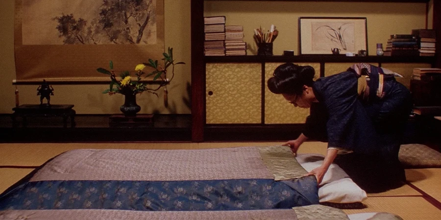 A staff of a ryokan fixing the futon bed inside the room (from "Gemini (1999)")