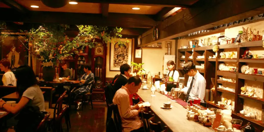 Baristas and customers socializing in a dimly-lit, traditional Japanese kissaten