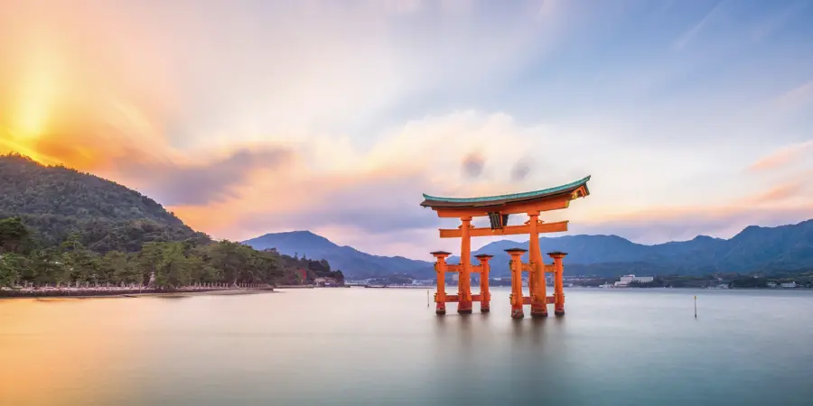 Torii gate floating on water at sunset in Miyajima Island