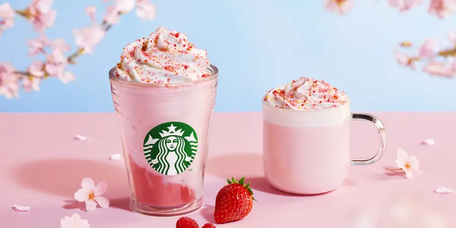 Pink starbucks sakura-themed drinks on a pink and blue backdrop with cherry blossoms and strawberries