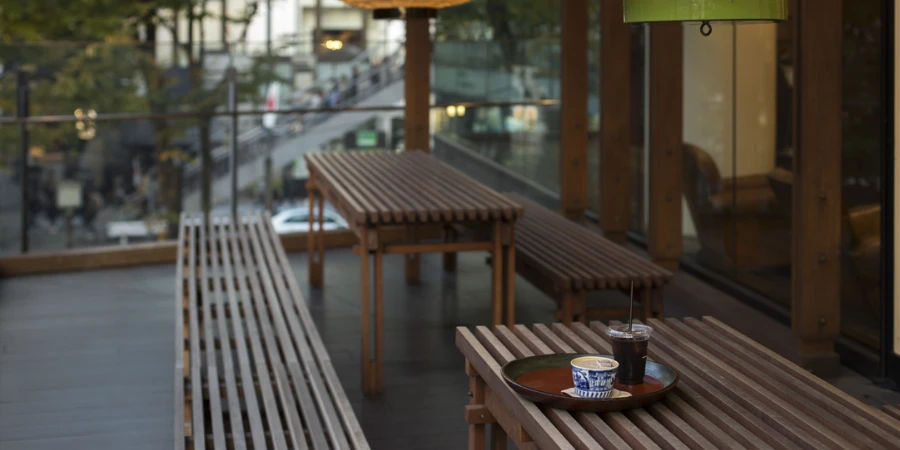 Wooden tables and benches, and a tray of coffee on a terrace
