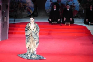 A woman standing out at the red carpet among the two men