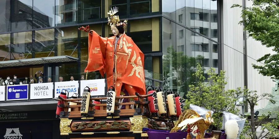 Decorated festival float with traditional performers during Kanda Matsuri in Tokyo, vibrant urban celebration blending modern cityscape with historic Japanese traditions.