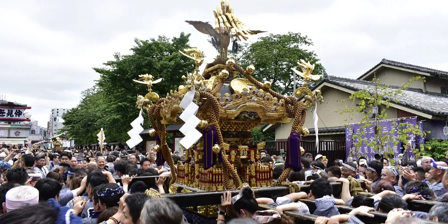 Crowd carrying a golden mikoshi portable shrine during Sanja Matsuri in Tokyo, energetic Japanese festival with participants celebrating traditional Shinto rituals.