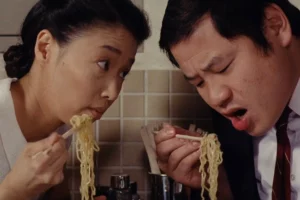 A man and a woman eating noodles (from the movie Tampopo)