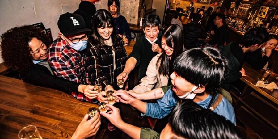 A group of people toasting drinks at a bar 