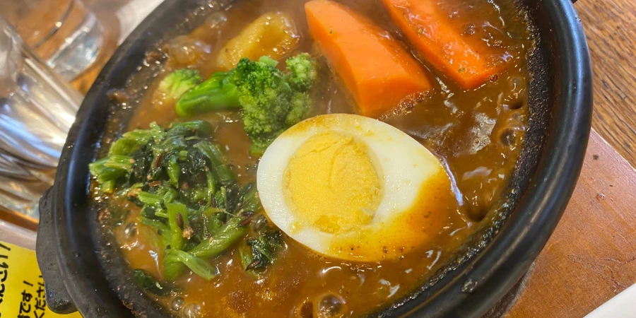 Beef tendon curry with an egg and vegetables on a hot plate