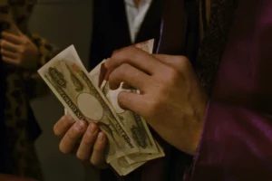 A person holding and counting Japanese Yen money