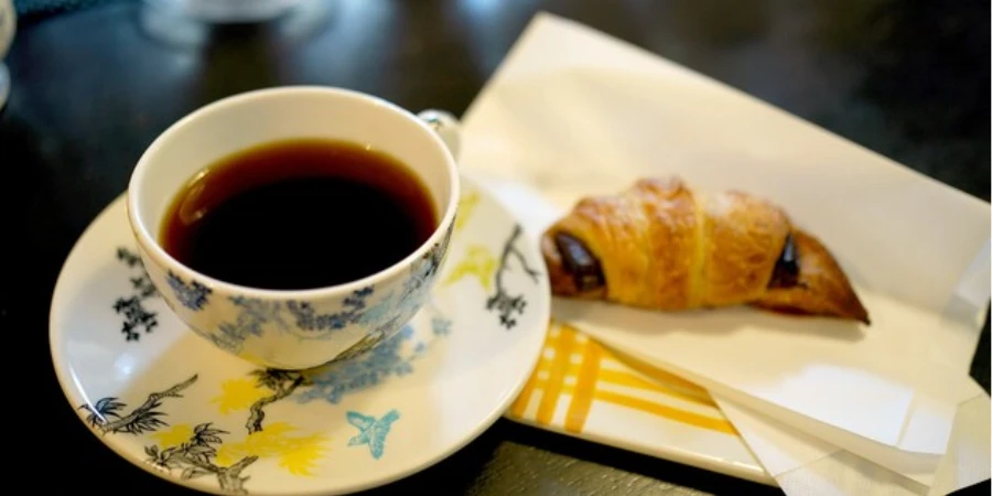 A cup of black coffee and a chocolate croissant
