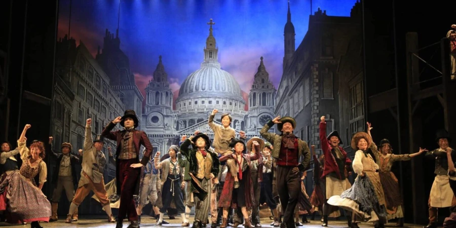 People dancing and smiling onstage for a musical