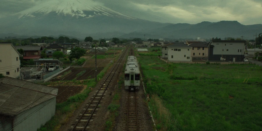 Japanese countryside rural train passing through train statin with mount fuji in the background. 