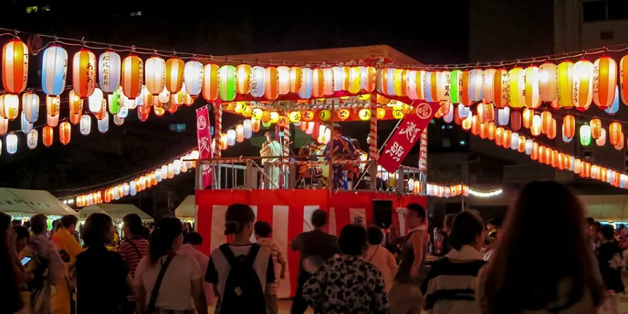 Visitors gathered around a lantern-lit yagura tower during the Bon Odori Festival, celebrating a traditional Japanese summer dance festival.