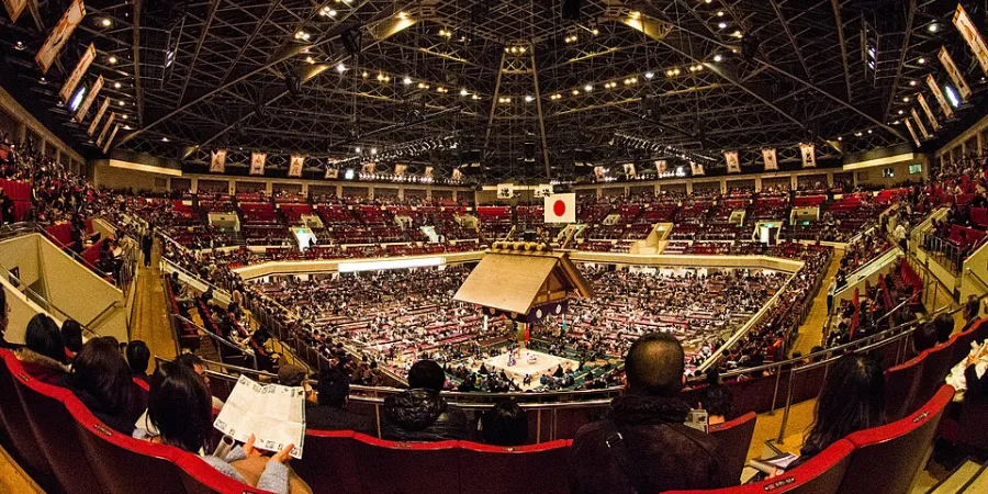 Grand Sumo Tournament in Tokyo with wrestlers competing in the dohyo at a packed sumo stadium