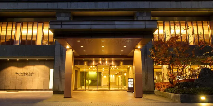 The exterior of Hearton Hotel Kyoto at night. Architecture is lit up with ambient outdoor lighting.