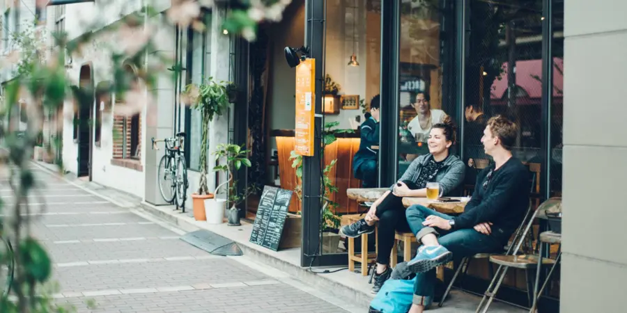 The exterior of Len Kyoto hostel with guests seated outside conversing.