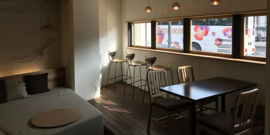 The interior of Santiago guesthouse. There's a lounge sofa, a desk, and bar stools facing a window.