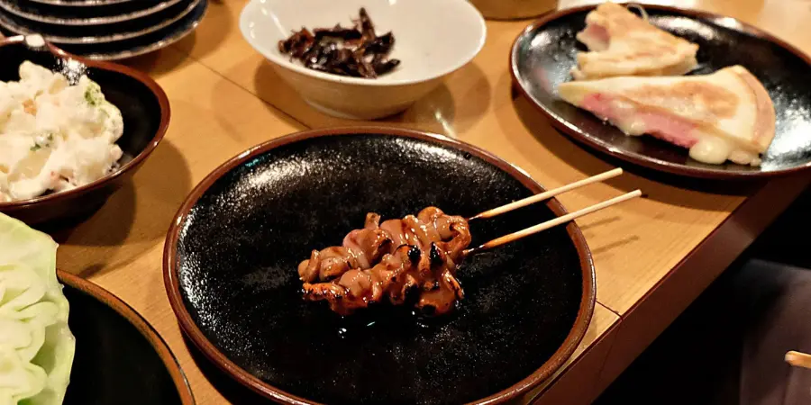 A plate of yakitori, or chicken grilled skewers with other side dishes in an izakaya pub in Koenji